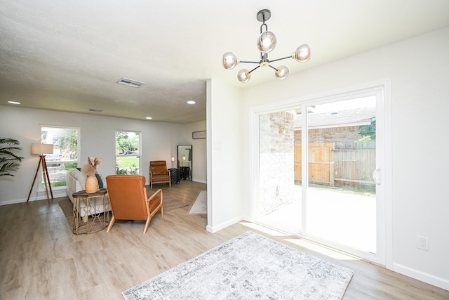 interior space with light wood finished floors, baseboards, visible vents, and a chandelier