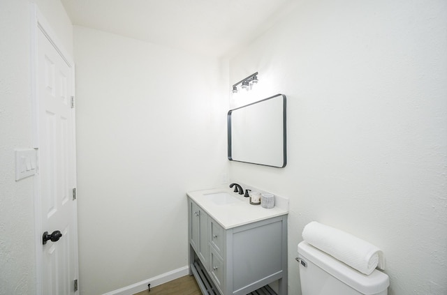 bathroom featuring toilet, vanity, wood finished floors, and baseboards
