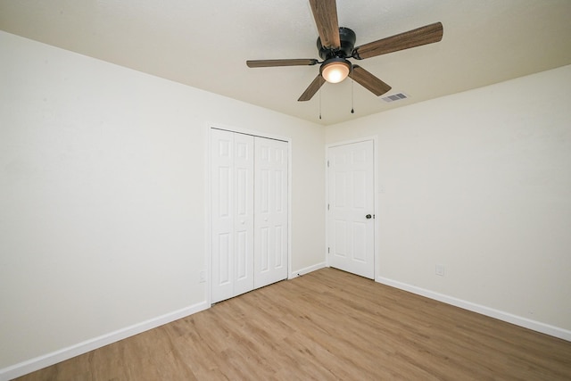 unfurnished bedroom with baseboards, visible vents, light wood-style floors, and a closet