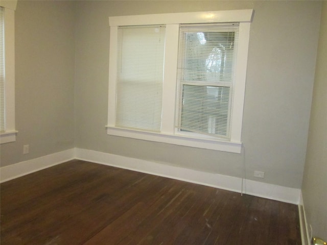 unfurnished room with baseboards and dark wood finished floors