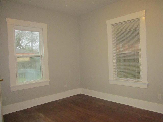 unfurnished room with baseboards and dark wood-type flooring