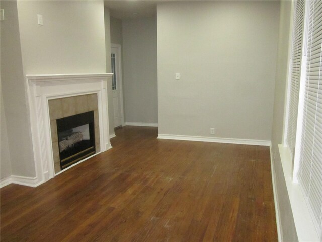 unfurnished living room featuring a fireplace, baseboards, and dark wood-style flooring