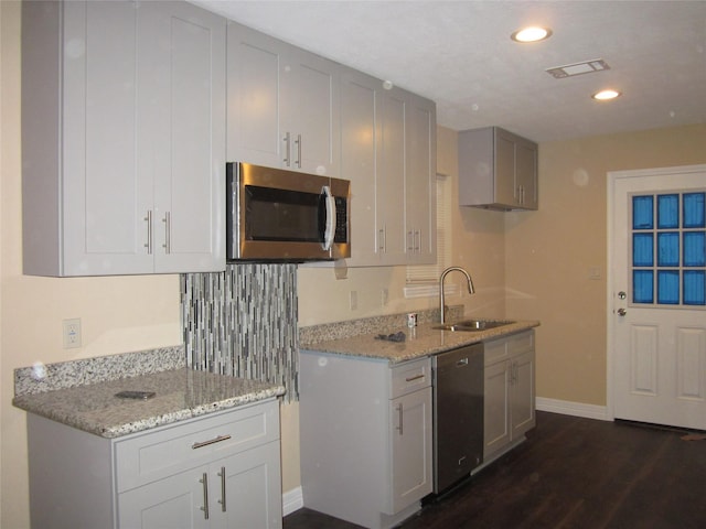 kitchen featuring baseboards, a sink, appliances with stainless steel finishes, and light stone counters