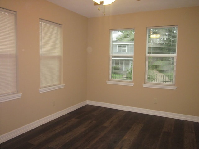empty room featuring a ceiling fan, baseboards, and dark wood-style flooring