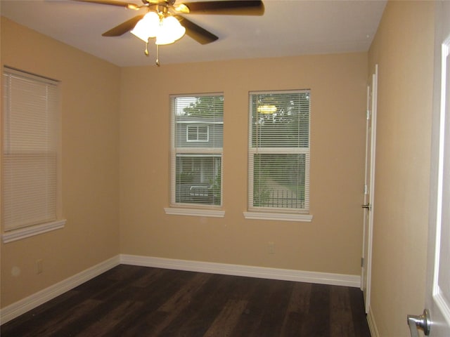 empty room with dark wood-type flooring, a ceiling fan, and baseboards