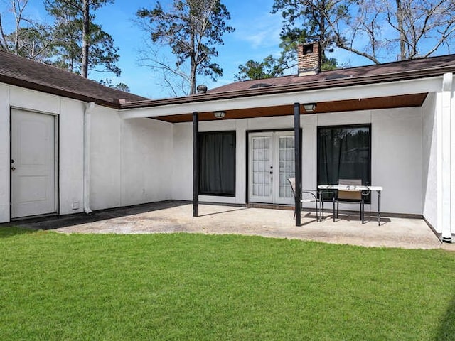 back of house with a chimney, french doors, a yard, and a patio