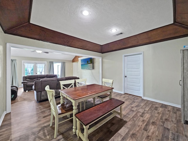 dining space with baseboards, wood finished floors, visible vents, and a textured ceiling