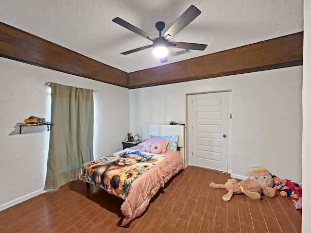 bedroom featuring visible vents, wood finished floors, baseboards, and a textured ceiling