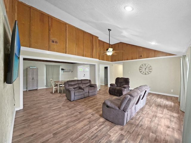 living area featuring baseboards, vaulted ceiling, ceiling fan, and wood finished floors