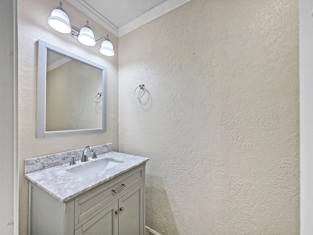 bathroom with a textured wall, vanity, and crown molding