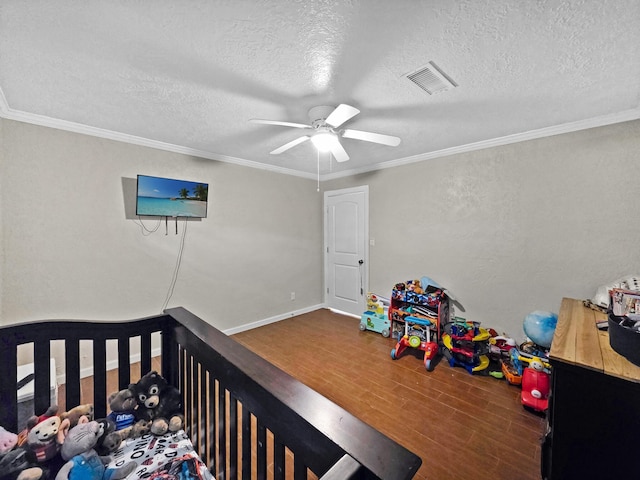 bedroom featuring a textured ceiling, wood finished floors, visible vents, and ornamental molding