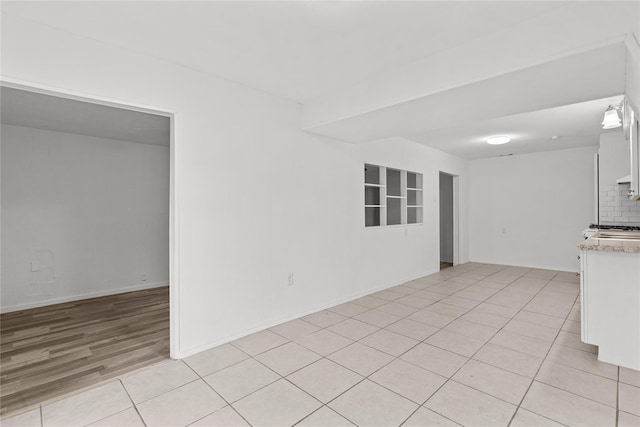 unfurnished living room with baseboards and light tile patterned floors