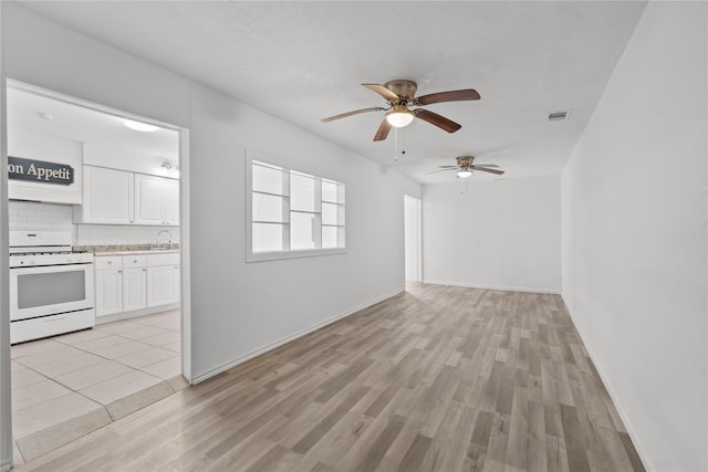 unfurnished living room featuring a sink, ceiling fan, light wood-style flooring, baseboards, and visible vents