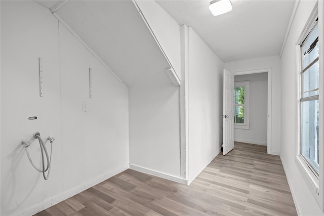 interior space with baseboards, hookup for a washing machine, laundry area, and light wood-type flooring