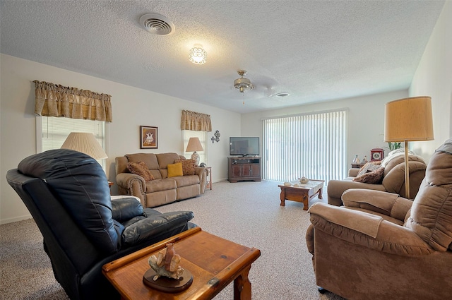 living area featuring a ceiling fan, a textured ceiling, baseboards, carpet flooring, and visible vents