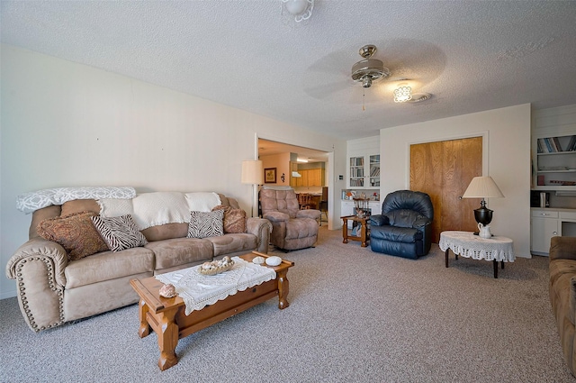 living area with a ceiling fan, carpet, and a textured ceiling