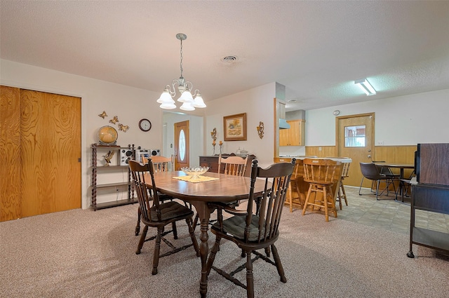 dining room with light colored carpet, an inviting chandelier, a textured ceiling, and visible vents