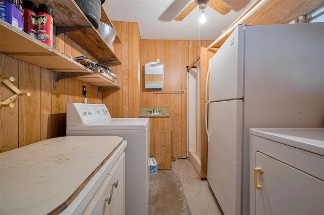 clothes washing area with a sink, washer and clothes dryer, ceiling fan, wooden walls, and laundry area