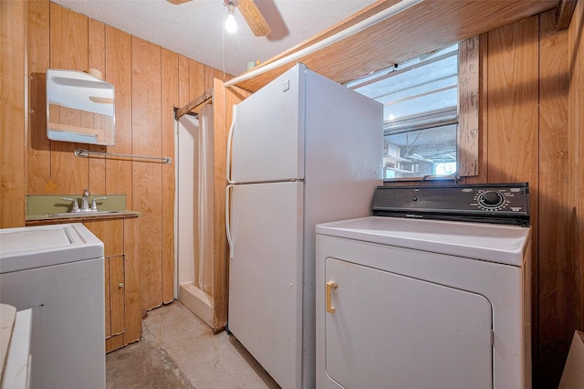 clothes washing area with washer and dryer, wood walls, a ceiling fan, and laundry area