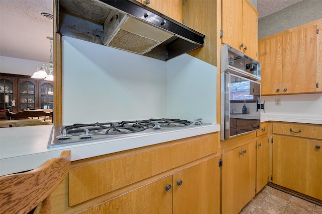 kitchen with white gas stovetop, oven, under cabinet range hood, and light countertops