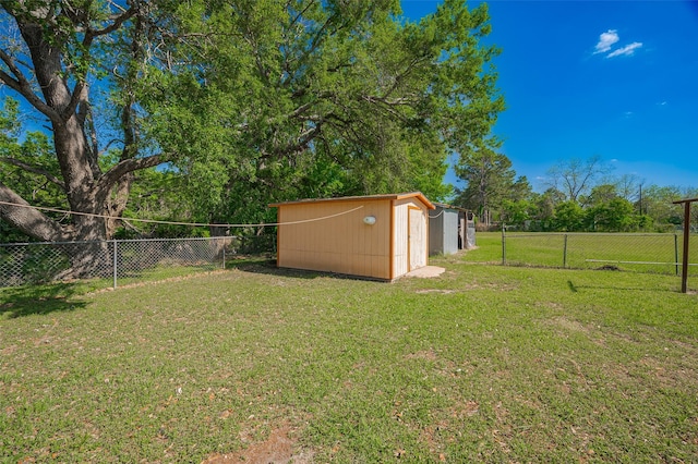 view of yard with a fenced backyard, an outbuilding, and a storage shed