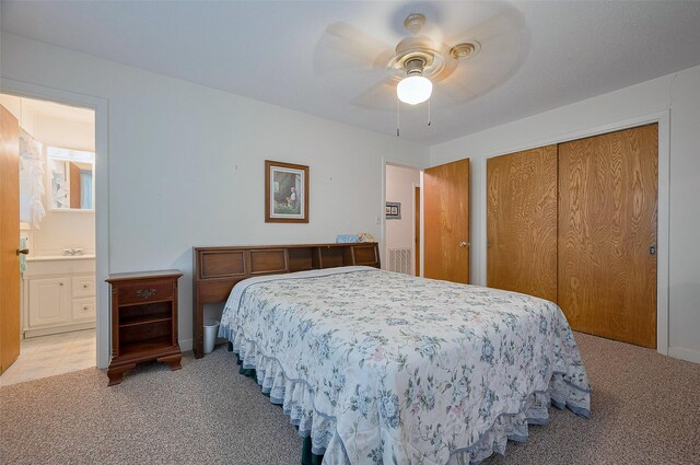 bedroom featuring light carpet, a ceiling fan, ensuite bath, and a closet