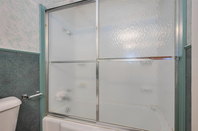 bathroom with bath / shower combo with glass door and toilet
