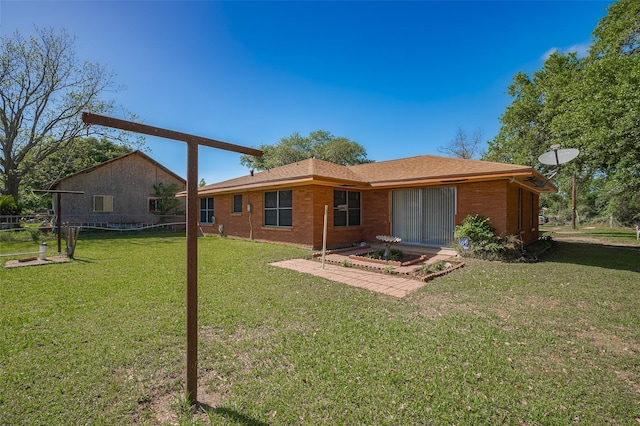 rear view of house with brick siding, a lawn, and fence