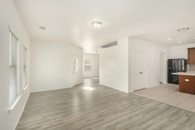1722 Caldbeck Ln, Fresno, TX 77545 - unfurnished living room with visible vents, arched walkways, light wood-style floors, and baseboards
