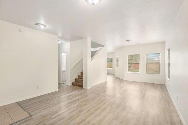 1722 Caldbeck Ln, Fresno, TX 77545 - unfurnished living room with baseboards, light wood finished floors, a wealth of natural light, and stairway