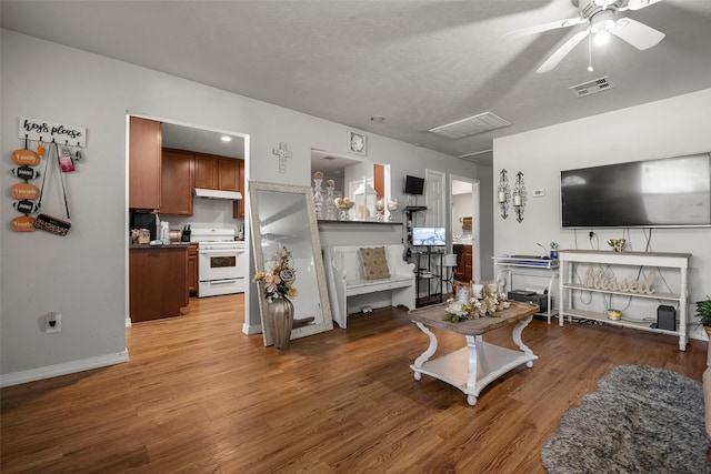 living area with baseboards, wood finished floors, visible vents, and ceiling fan