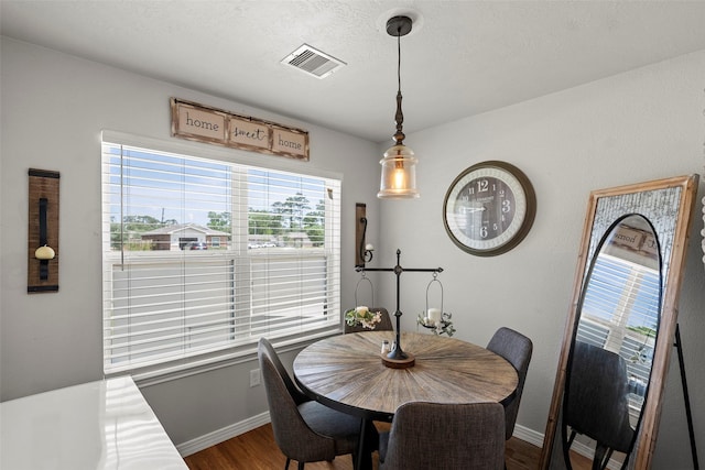 dining space featuring baseboards, dark wood-style flooring, visible vents, and plenty of natural light