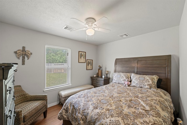 bedroom featuring wood finished floors, visible vents, a ceiling fan, and baseboards
