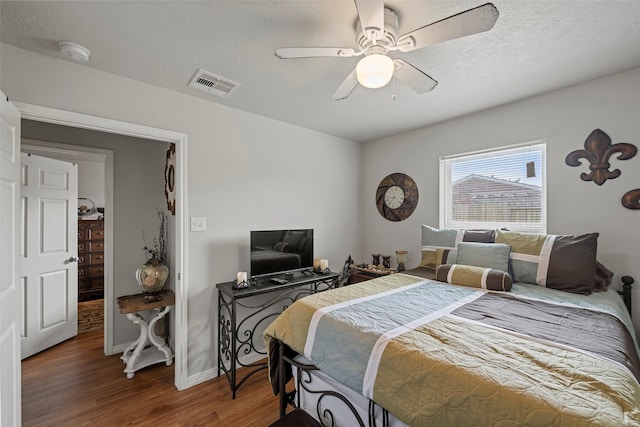 bedroom with wood finished floors, visible vents, baseboards, and ceiling fan