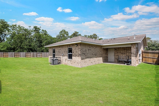back of property with a fenced backyard, brick siding, and a yard