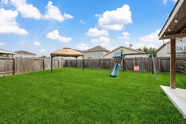 view of yard featuring a gazebo, a playground, and a fenced backyard