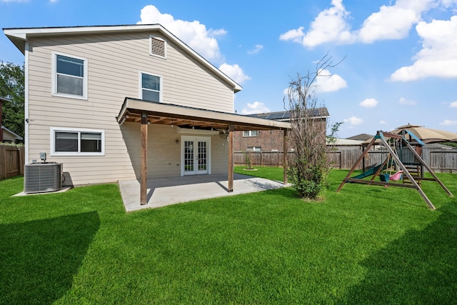 rear view of house with a patio area, a fenced backyard, a lawn, a playground, and french doors
