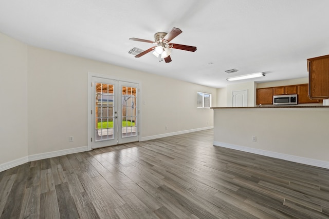 unfurnished living room featuring dark wood finished floors, baseboards, visible vents, and ceiling fan