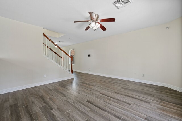 unfurnished living room with wood finished floors, stairs, ceiling fan, baseboards, and visible vents