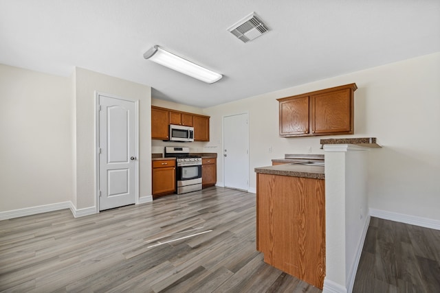 kitchen featuring visible vents, appliances with stainless steel finishes, brown cabinetry, and light wood-style floors