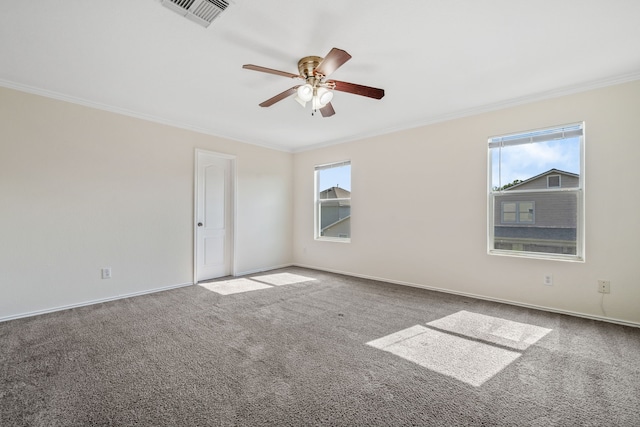 spare room with carpet flooring, visible vents, ceiling fan, baseboards, and ornamental molding
