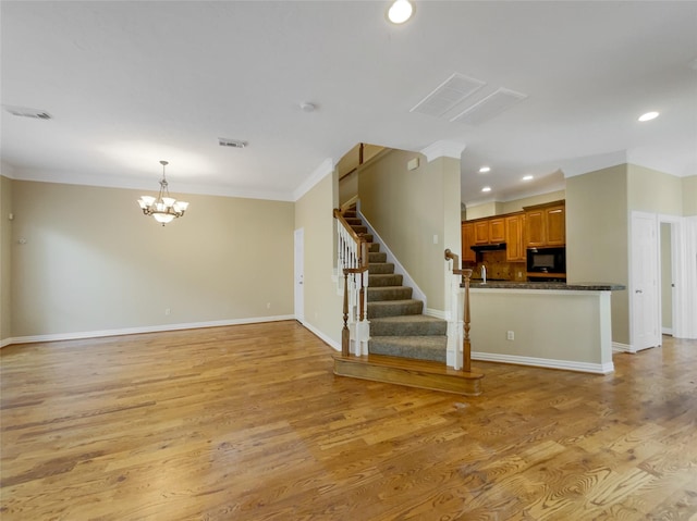 12620 Briar Patch Rd, Houston, TX 77077 - unfurnished living room featuring light wood-style flooring, visible vents, an inviting chandelier, and ornamental molding