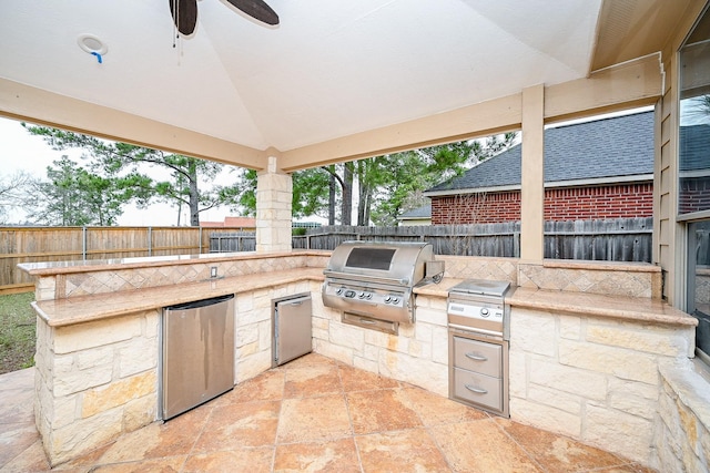 view of patio featuring a fenced backyard, area for grilling, a ceiling fan, and exterior kitchen