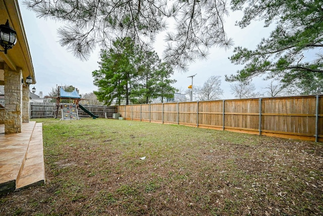 view of yard with a fenced backyard and a playground