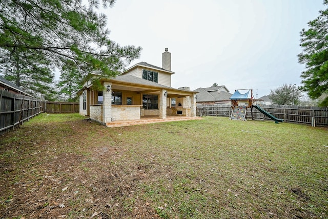 back of property featuring a lawn, a chimney, a fenced backyard, and a playground