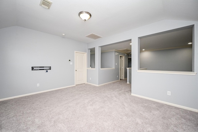 carpeted spare room with baseboards, visible vents, and vaulted ceiling