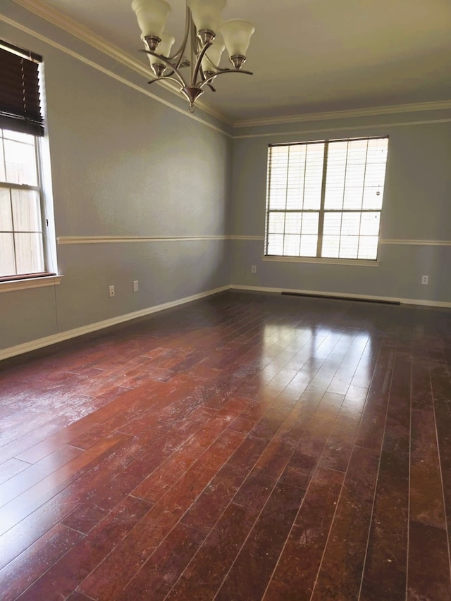 unfurnished room featuring a chandelier, baseboards, ornamental molding, and wood-type flooring