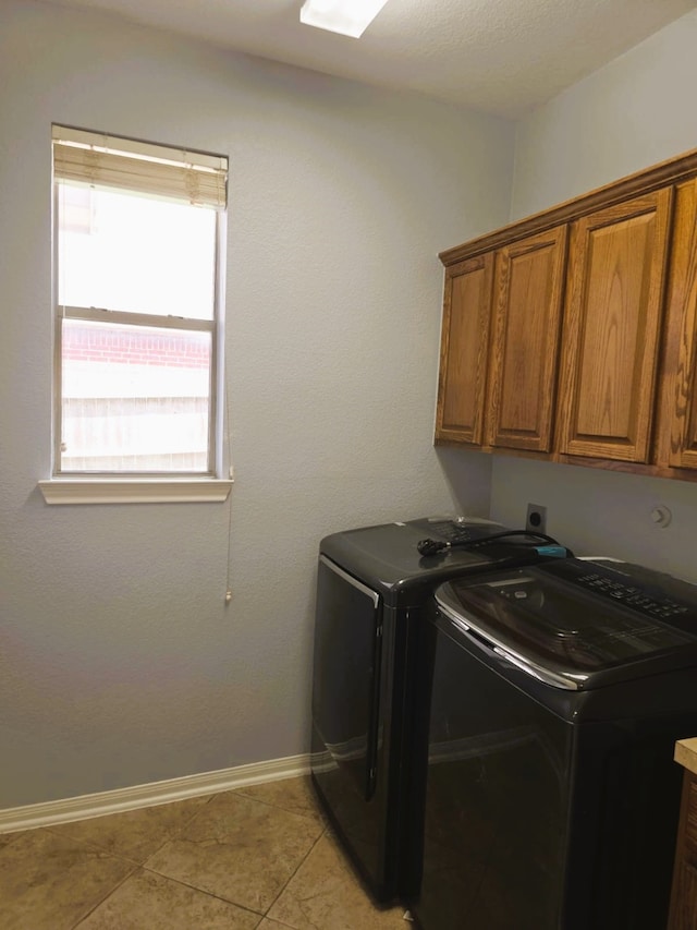 washroom featuring baseboards, light tile patterned flooring, cabinet space, and washer and clothes dryer