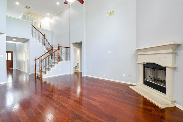 1106 Windsor Chase Ln, Spring, TX 77373 - unfurnished living room with a towering ceiling, hardwood / wood-style floors, stairs, a ceiling fan, and a fireplace with raised hearth