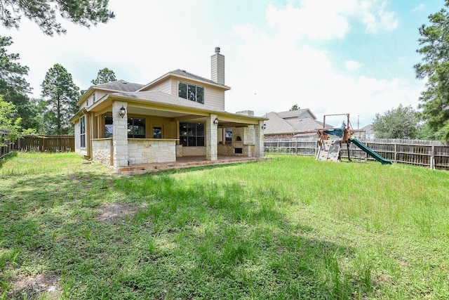 1106 Windsor Chase Ln, Spring, TX 77373 - back of property featuring a playground, a chimney, stone siding, and roof with shingles